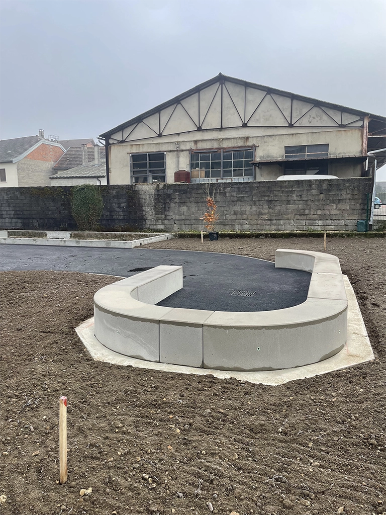 aménagement cour d'école avec une partie en terre végétale et l'autre en enrobé en cours de réalisation avec des formes sinusoïdales et pose de banc béton