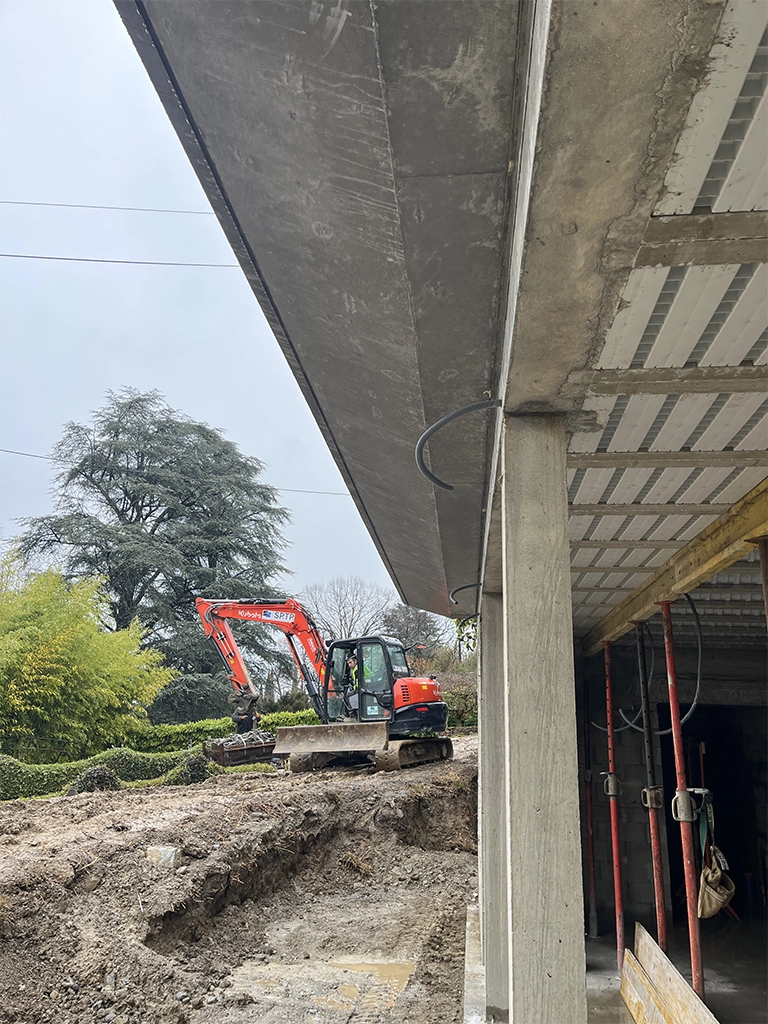 construction maçonné avec casquette béton et engin de chantier en fond