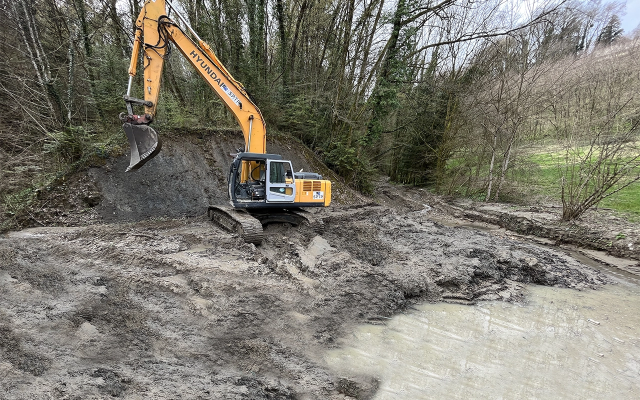 Pelleteuse en train de curer une plage de dépôt d'une rivière