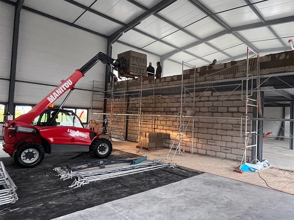 Construction d'un mur maçonné par des ouvriers dans un bâtiment et transpalette