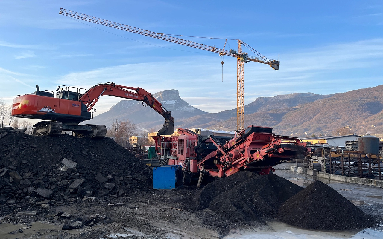 recyclage et concassage des matériaux sur le dépôt de l'entreprise SPTP avec en fond une grue et la montagne Le Granier